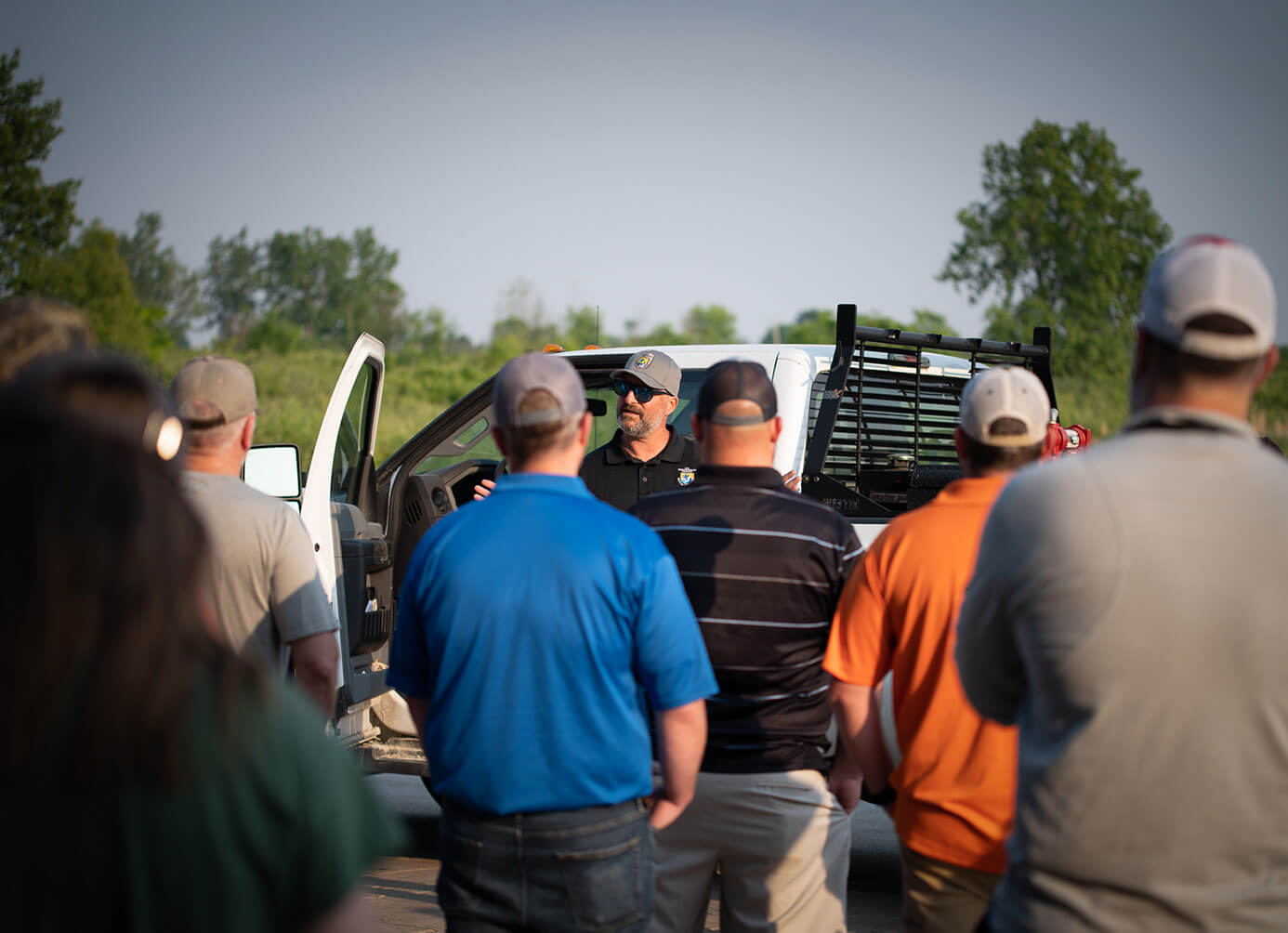 Community members being talked to in field with truck
