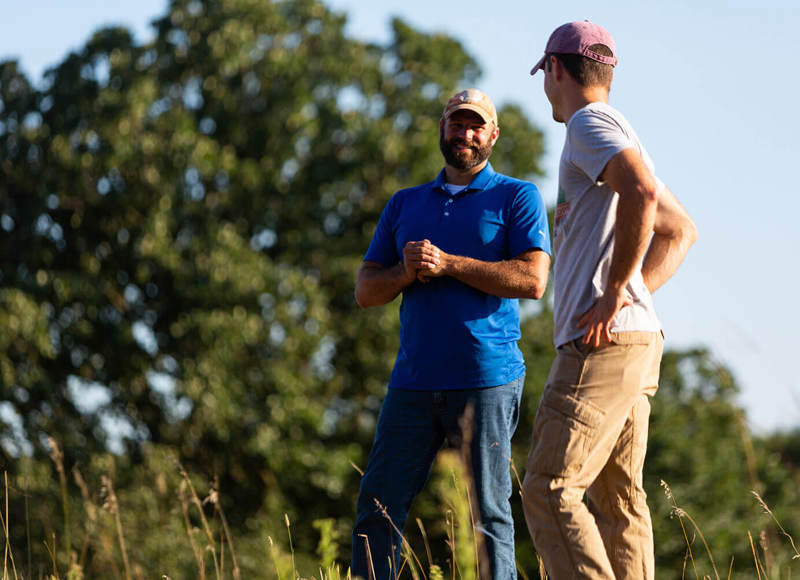 Two staff members outside and in front of a tree